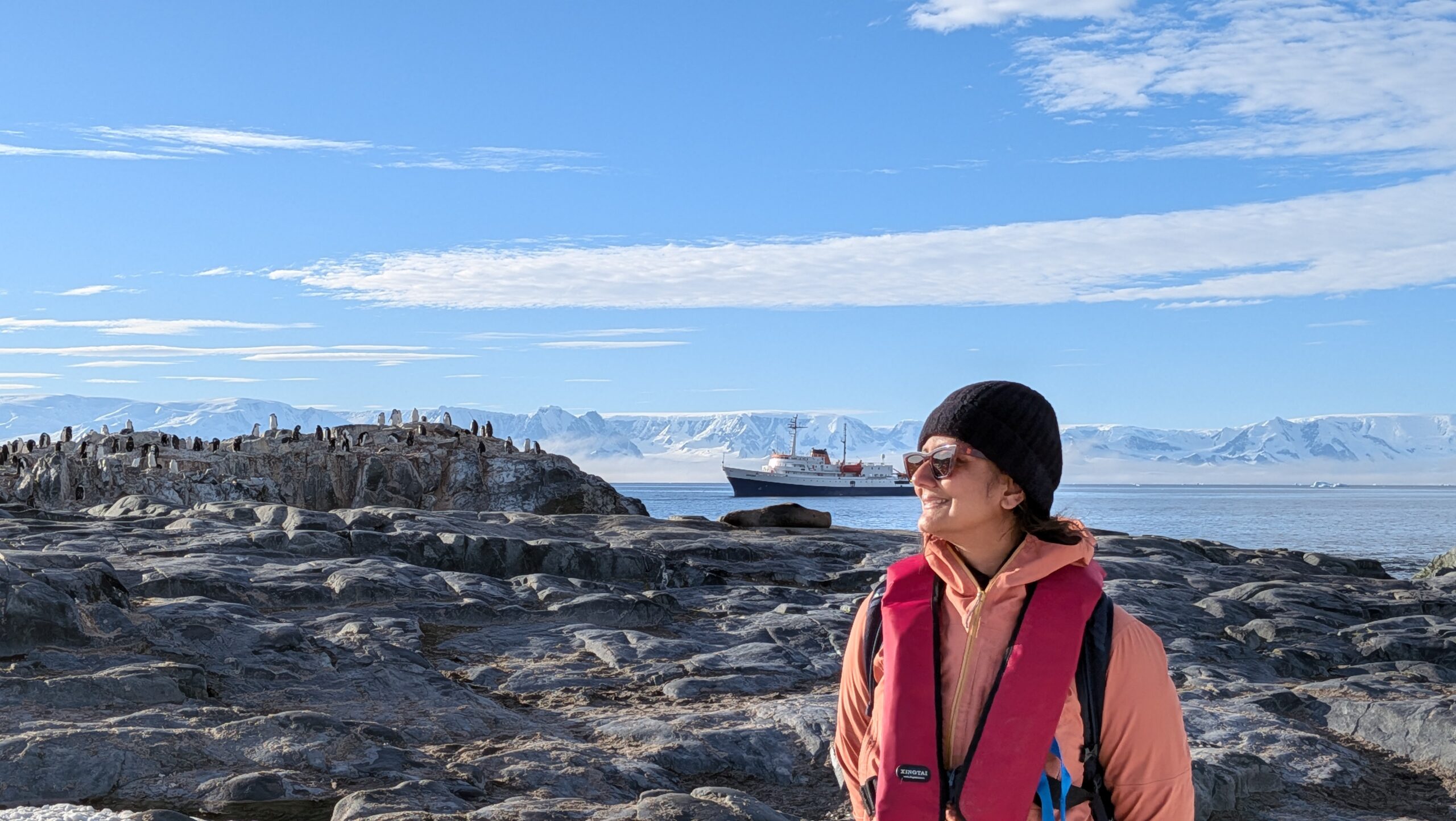 a Zodiac approaching the shore of Half Moon Island, lined with penguins and glaciers