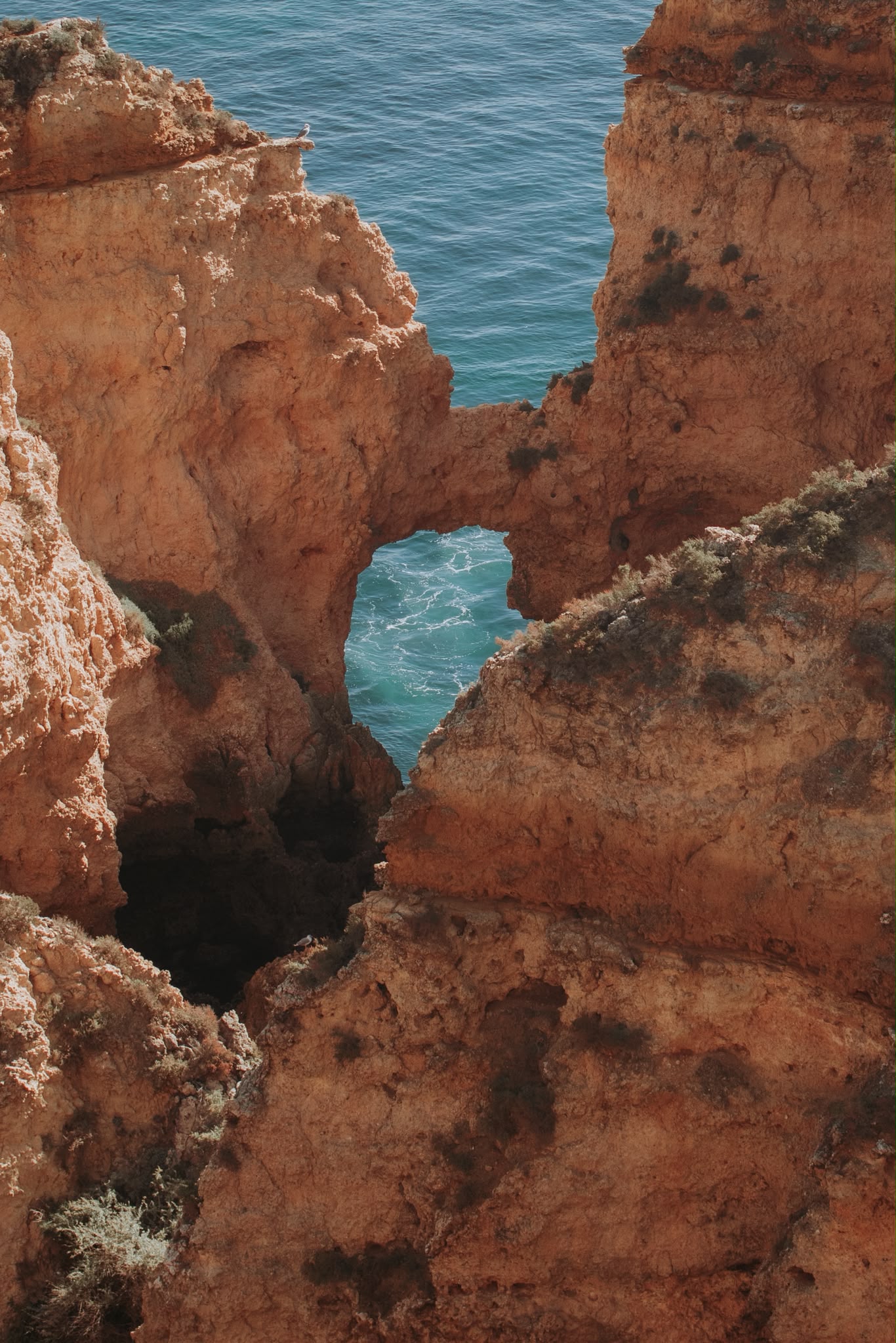 Golden sandstone cliffs and a sea arch above turquoise water on the Lagos coast, Portugal