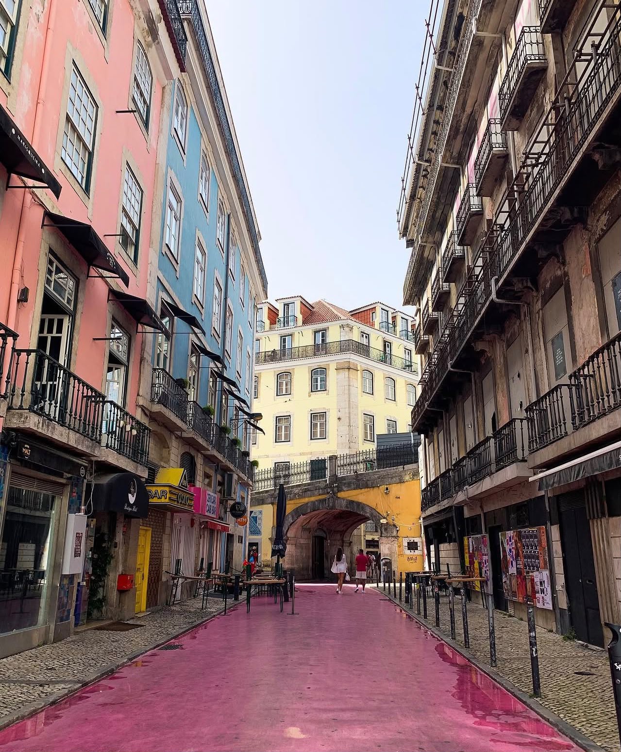 A pink-painted street lined with pastel buildings in Lisbon, Portugal